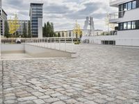 an empty sidewalk in front of two tall buildings with clouds overhead and some building blocks