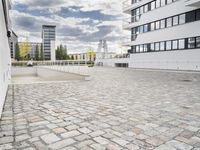 an empty sidewalk in front of two tall buildings with clouds overhead and some building blocks