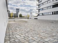 an empty sidewalk in front of two tall buildings with clouds overhead and some building blocks