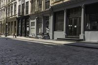 an empty sidewalk in front of a row of buildings with a clock at the end