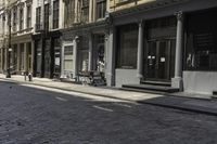 an empty sidewalk in front of a row of buildings with a clock at the end