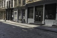 an empty sidewalk in front of a row of buildings with a clock at the end