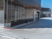 the sidewalk in front of the building is empty and has a red stop sign on it