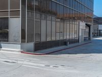 the sidewalk in front of the building is empty and has a red stop sign on it