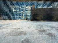 the view of an empty sidewalk in front of a tall building with blue glass on its side