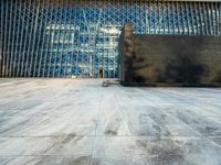 the view of an empty sidewalk in front of a tall building with blue glass on its side