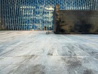 the view of an empty sidewalk in front of a tall building with blue glass on its side