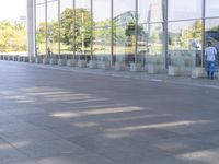 the sidewalk is empty outside of this modern city building on a sunny day, with people walking on the side