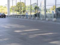 the sidewalk is empty outside of this modern city building on a sunny day, with people walking on the side