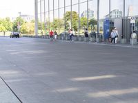 the sidewalk is empty outside of this modern city building on a sunny day, with people walking on the side