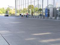 the sidewalk is empty outside of this modern city building on a sunny day, with people walking on the side