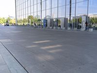 the sidewalk is empty outside of this modern city building on a sunny day, with people walking on the side