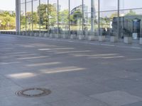 the sidewalk is empty outside of this modern city building on a sunny day, with people walking on the side