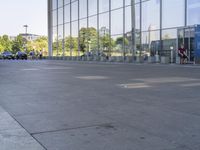 the sidewalk is empty outside of this modern city building on a sunny day, with people walking on the side