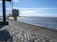 the sidewalk is empty near the water and the railing is leaning in front of the building