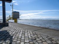 the sidewalk is empty near the water and the railing is leaning in front of the building