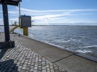 the sidewalk is empty near the water and the railing is leaning in front of the building