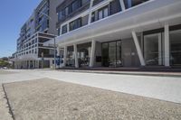 the sidewalk is empty with cars in the background and on each side the sidewalk is a large building with many windows and glass