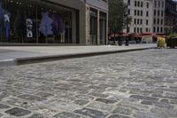 there is an empty sidewalk on the street with people walking on it and a store window on the corner