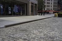 there is an empty sidewalk on the street with people walking on it and a store window on the corner