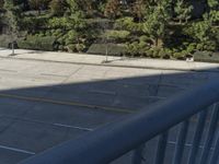 the sidewalk is empty and there are trees on either side of the road below the sidewalk