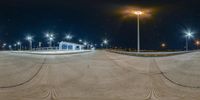 an empty skateboard park lit up at night time near street lamps and a street light