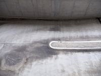 the empty skate board ramp sits in the concrete area next to a cement bench and railing