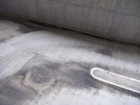 the empty skate board ramp sits in the concrete area next to a cement bench and railing