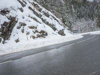 the road is very slippery and empty on a snowy day near a pine tree lined mountain