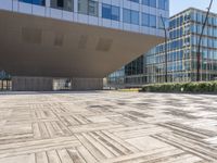 the empty square at a large office building with many windows and wooden floor tiles in front of it