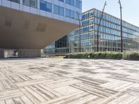 the empty square at a large office building with many windows and wooden floor tiles in front of it