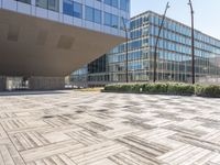 the empty square at a large office building with many windows and wooden floor tiles in front of it