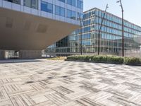 the empty square at a large office building with many windows and wooden floor tiles in front of it