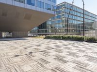 the empty square at a large office building with many windows and wooden floor tiles in front of it