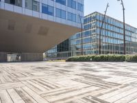 the empty square at a large office building with many windows and wooden floor tiles in front of it