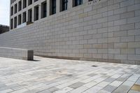 there is an empty stone block outside the building on a sunny day on a sidewalk