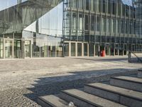 an empty stone sidewalk with some glass buildings around it on the other side of the street