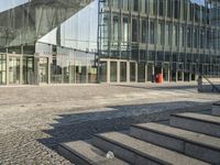 an empty stone sidewalk with some glass buildings around it on the other side of the street