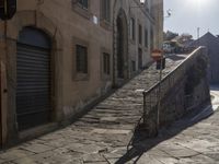 an empty stone street with lots of stairs leading to buildings and a person on a skateboard