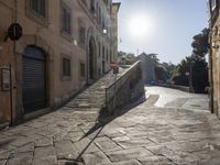 an empty stone street with lots of stairs leading to buildings and a person on a skateboard