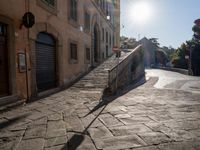 an empty stone street with lots of stairs leading to buildings and a person on a skateboard