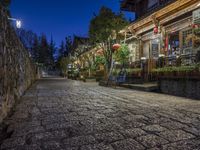 an empty stone street in an old chinese city at night with red lanterns and green trees in the background