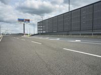 the empty street near an airport is surrounded by large billboards that read ber