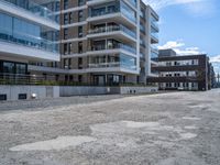 an empty street in the middle of an apartment complex with a parking space and glass walls