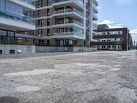 an empty street in the middle of an apartment complex with a parking space and glass walls