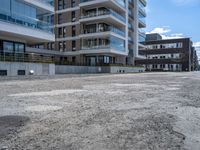 an empty street in the middle of an apartment complex with a parking space and glass walls