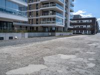 an empty street in the middle of an apartment complex with a parking space and glass walls