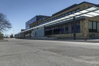 empty street with benches on either side and large glass windows on the other side of it