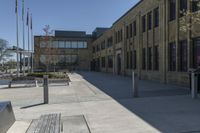 the empty street in front of the school is empty and it has benches on the curb