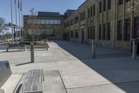 the empty street in front of the school is empty and it has benches on the curb